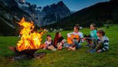 Ein Lagerfeuer mit Kinder die Lieder singen.
