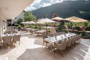Sonnige Terrasse mit stilvoll gedeckten Tischen im Familienhotel Kindl.