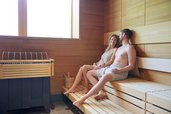 Eltern entspannen in der Sauna des Familienhotels Das Bayrischzell auf den Holzbänken in ruhiger Atmosphäre.