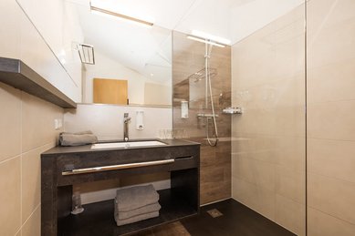 Modernes Badezimmer im Familienhotel Oberkarteis mit offener Dusche, großem Spiegel und stilvollem Waschtisch.