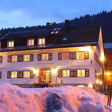 Familienhotel Sonne Bezau in Vorarlberg umgeben von einer winterlichen Landschaft.