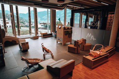 Indoor Spielbereich im Familienhotel Mia Alpina in Tirol mit Sitzlounge, Spielteppich, großen Fenstern und Bergblick.