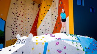 Ein Mädchen steht vor der riesigen Boulder- und Kletterwand im Bobo Fun Park im Kolping Family Resort in Ungarn.