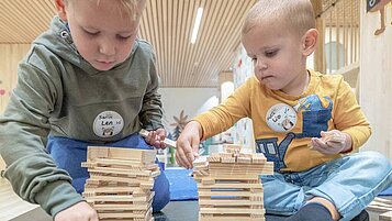 Kinder sitzen in der Kinderbetreuung am Basteltisch und basteln ein Nest mit ihrer Betreuerin im Familienhotel Gorfion in Lichtenstein.