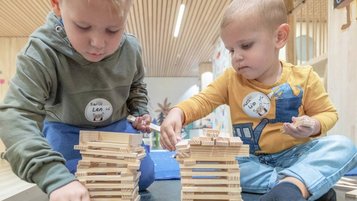 Kinder sitzen in der Kinderbetreuung am Basteltisch und basteln ein Nest mit ihrer Betreuerin im Familienhotel Gorfion in Lichtenstein.