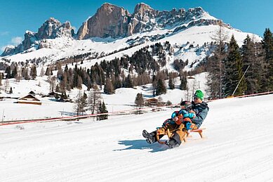 Vater und Sohn rodeln in Südtirol die Piste runter, bevor es wieder ins Familienhotel Engel Gourmet & Spa geht.
