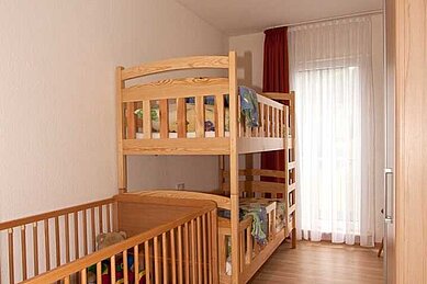 Kinderschlafbereich im Familienzimmer mit einem Hochbett und einem Babybett.