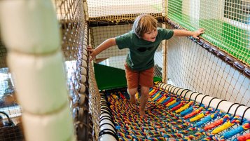 Junge tobt im bunten Indoor-Spielbereich des Familien Resort Petschnighof in Kärnten.