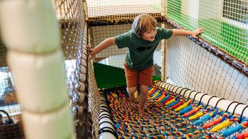 Junge tobt im bunten Indoor-Spielbereich des Familien Resort Petschnighof in Kärnten.