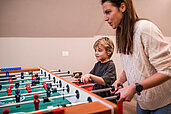 Mutter und Sohn spielen Tischkicker im Familienhotel Alpenhof Dolomit Family