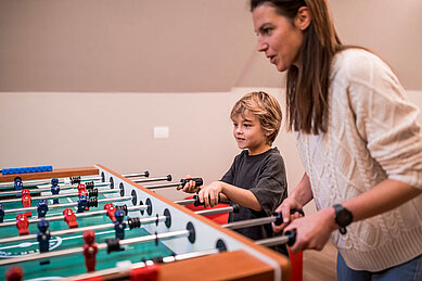 Mutter und Sohn spielen Tischkicker im Familienhotel Alpenhof Dolomit Family