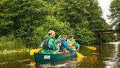 Familie fährt mit dem Kanu über einen See in der Mecklenburgischen Seenplatte.