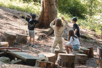 Kinder spielen mit Naturmaterialien im Waldspielbereich des Familienhotels Huber in Südtirol
