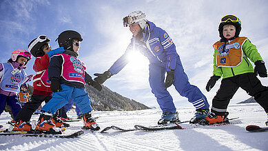 Kinder beim Skifahren in der Skischule im Familienhotel Huber in Südtirol.