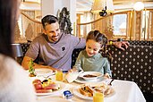 Vater und Tochter sitzen am Frühstückstisch im Familienhotel Alpenhotel Kindl in Tirol.