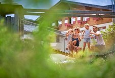 Eine Familie auf einer Hängebrücke auf dem Spielplatz im Familienhotel Amiamo im Salzburger Land