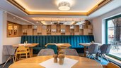 Moderne Stube mit Holztischen und Sitzbänken im Familienhotel Ottonenhof.