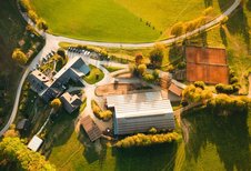 Luftaufnahme vom Familienhotel Ponyhof in Kärnten mit Reithalle, Tennisplätzen und umliegender Herbstlandschaft.