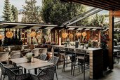 Familienhotel Mia Alpina in Tirol mit überdachter Restaurantterrasse, gedeckten Tischen und viel Grün.