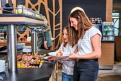 Mutter und Tochter bedienen sich am Buffet im Restaurant des Familienhotels Aigo welcome family in Oberösterreich
