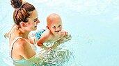 Mutter mit Baby im Schwimmbecken im Familienhotel Aigo welcome family in Oberösterreich