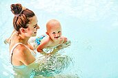 Mutter mit Baby im Schwimmbecken im Familienhotel Aigo welcome family in Oberösterreich