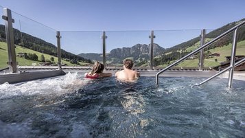 Eltern entspannen im Sprudelpool des Familienhotels Galtenberg mit Blick auf die umliegende Berglandschaft.
