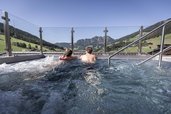 Eltern entspannen im Sprudelpool des Familienhotels Galtenberg mit Blick auf die umliegende Berglandschaft.