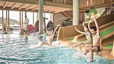 Kinder rutschen im Familienhotel Mia Alpina in Tirol auf der Wasserrutsche ins Hallenbad.