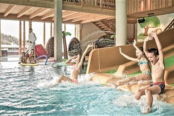 Kinder rutschen im Familienhotel Mia Alpina in Tirol auf der Wasserrutsche ins Hallenbad.