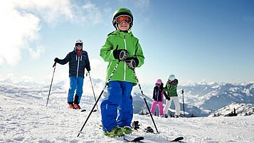 Junge steht auf Skiern auf der Piste im familienfreundlichen Skigebiet im Salzburger Land.