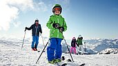 Junge steht auf Skiern auf der Piste im familienfreundlichen Skigebiet im Salzburger Land.