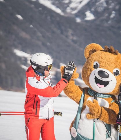 Vater und Tochter beim Skifahren in den Dolomiten gemeinsam mit dem Maskottchen des Familienhotels Alpenhof Dolomit Family