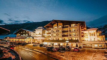 Außenansicht des Familienhotels Alpenhotel Kind in Tirol bei Nacht. Das Hotel ist schön beleuchtet und liegt direkt am familienfreundlichen Skigebiet. 