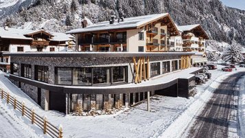 Außenansicht des Familienhotels Alpenhotel Kind in Tirol bei Nacht. Das Hotel ist schön beleuchtet und liegt direkt am familienfreundlichen Skigebiet. 