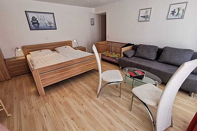 Ein Doppelzimmer mit Kinderbett im Familienhotel Monikas Ferienhof Sauerland.
