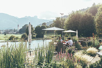Eine Familie sitzt am See beim Frühstücken vom Familienhotel Post Family Resort im Salzburger Land.
