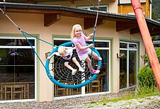 Kinder spielen in der Nestschaukel im Familienhotel Lärchenhof in Tirol