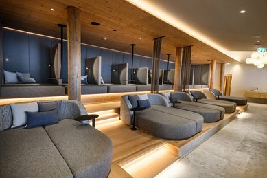Moderner Ruheraum im Zauchenseehof mit großen, gepolsterten Liegeinseln, erhöhten Relaxnischen und warmer indirekter Beleuchtung aus Holz- und Stoffelementen.