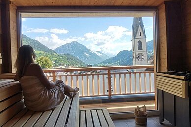 Frau in der Sauna des Kinderhotels Stefan in Österreich. Von der Sauna hat man einen schönen Panoramablick in die umliegende Berglandschaft.