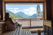 Frau in der Sauna des Kinderhotels Stefan in Österreich. Von der Sauna hat man einen schönen Panoramablick in die umliegende Berglandschaft.