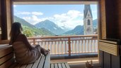 Frau in der Sauna des Kinderhotels Stefan in Österreich. Von der Sauna hat man einen schönen Panoramablick in die umliegende Berglandschaft.