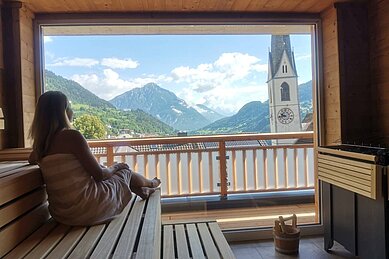 Frau in der Sauna des Kinderhotels Stefan in Österreich. Von der Sauna hat man einen schönen Panoramablick in die umliegende Berglandschaft.