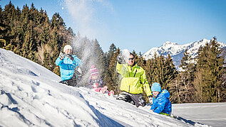 Familie tobt im Schnee.