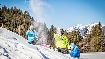 Familie tobt im Schnee.