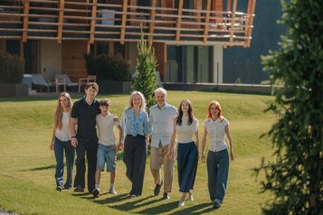 Die Gastgeberfamilie Thöni läuft über die grüne Wiese vor dem Familienhotel Bella Vista in Südtirol.