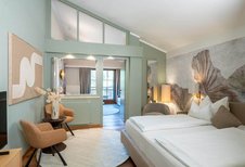 Modern eingerichtetes Familienzimmer mit Doppelbett, Sitzecke und Balkon im Familienhotel Post.