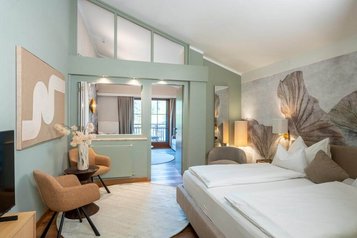 Modern eingerichtetes Familienzimmer mit Doppelbett, Sitzecke und Balkon im Familienhotel Post.