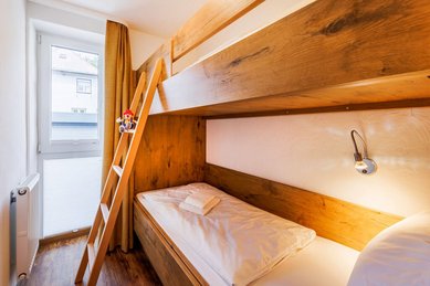 Gemütliches Etagenbett aus Holz mit Leiter und Einzelbett im Familienzimmer des Hotel Engel im Schwarzwald