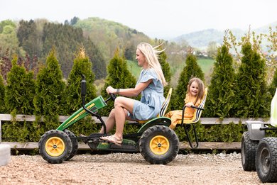 Mutter und Tochter fahren im Familienhotel gemeinsam mit einem Trettraktor über eine kleine Rennstrecke